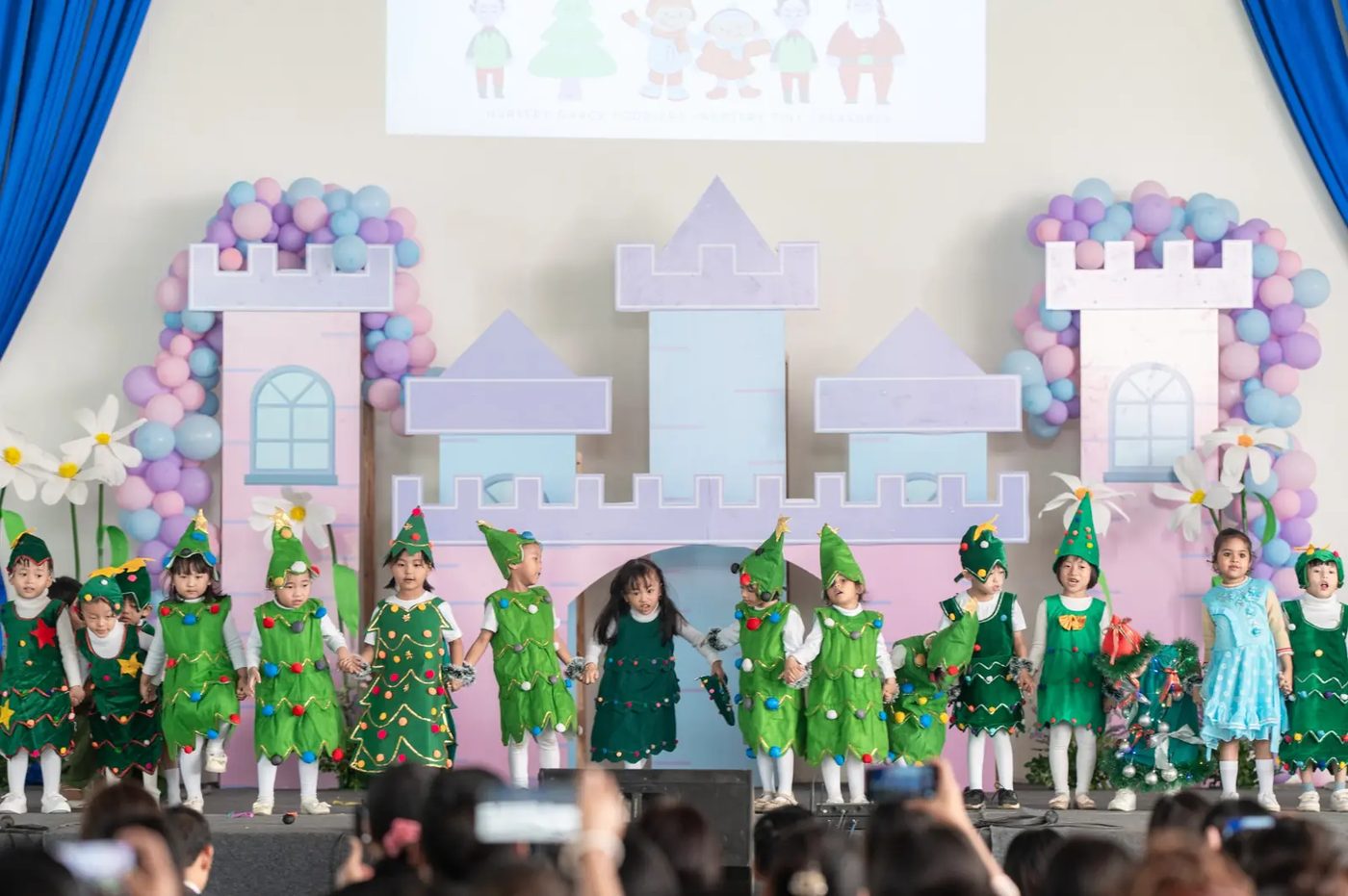 Kindergarten students in Christmas tree costumes on stage